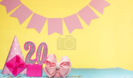 Foto de Fecha de nacimiento para una niña de 20 años. Copiar espacio. Cumpleaños en tonos rosados con un fondo amarillo. Decoraciones con velas numeradas y una caja de regalo. Tarjeta de aniversario para una mujer - Imagen libre de derechos