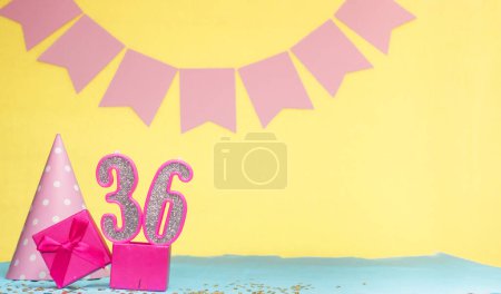 Date of birth for a girl  36. Copy space. Birthday in pink shades with a yellow background. Decorations with numbered candles and a gift box. Anniversary card for a woman