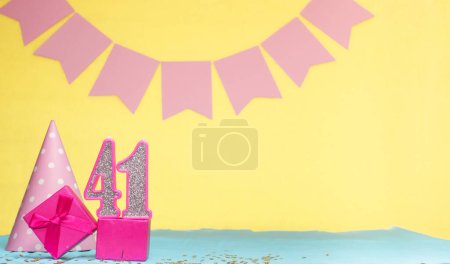 Foto de Fecha de nacimiento para una niña 41. Copiar espacio. Cumpleaños en tonos rosados con un fondo amarillo. Decoraciones con velas numeradas y una caja de regalo. Tarjeta de aniversario para una mujer - Imagen libre de derechos