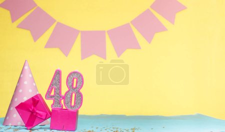 Date of birth for a girl  48. Copy space. Birthday in pink shades with a yellow background. Decorations with numbered candles and a gift box. Anniversary card for a woman
