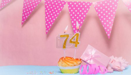 Fecha de nacimiento 74. Tarjeta de felicitación en tonos rosados. Números de velas de aniversario. Chica feliz cumpleaños, decoración de guirnalda de lunares. Copiar espacio.