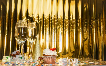 Birthday background with pudding pie. Scenery festive glasses of champagne, anniversary in golden color. Copy space. Happy birthday postcard.