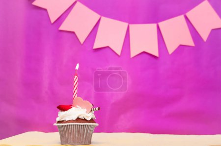 Birthday background with cupcake. Pink background with a cake and burning candles, save space, happy birthday anniversary for a girl. Holiday pudding muffin.
