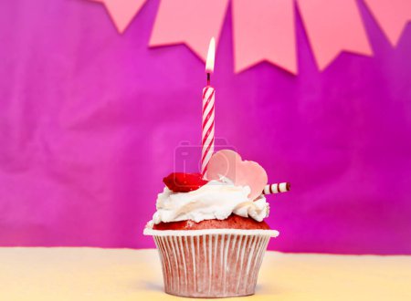 Birthday background with cupcake. Pink background with a cake and burning candles, save space, happy birthday anniversary for a girl. Holiday pudding muffin.