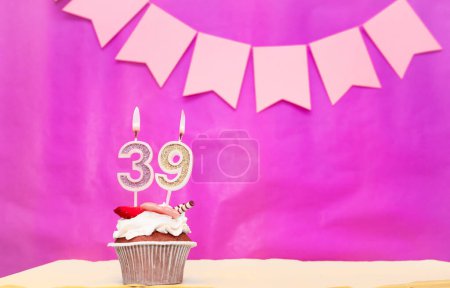 Background date of birth with number  39. Pink background with a cake and burning candles, save space, happy birthday anniversary for a girl. Holiday pudding muffin.