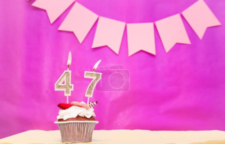 Date de naissance avec le numéro 47. Fond rose avec un gâteau et des bougies allumées, économiser de l'espace, joyeux anniversaire pour une fille. Muffin au pudding de vacances.