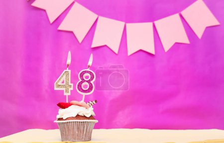 Background date of birth with number  48. Pink background with a cake and burning candles, save space, happy birthday anniversary for a girl. Holiday pudding muffin.