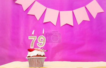 Background date of birth with number  79. Pink background with a cake and burning candles, save space, happy birthday anniversary for a girl. Holiday pudding muffin.