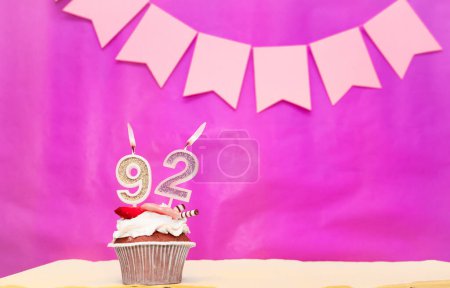 Hintergrund Geburtsdatum mit der Nummer 92. Pinkfarbener Hintergrund mit einer Torte und brennenden Kerzen, platzsparend, alles Gute zum Geburtstag für ein Mädchen. Ferienpudding-Muffin.