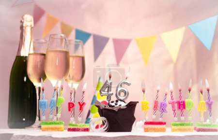 Cumpleaños con champán y copas. Vela de cumpleaños con número 46. Tarjeta de aniversario con guirnaldas ahorrar espacio. Fondo festivo.