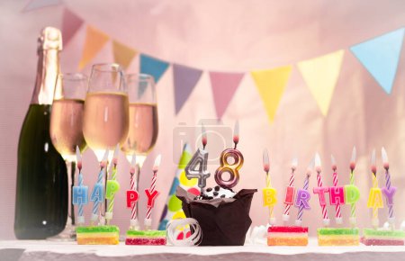 Birthday with champagne and glasses. Birthday candle with number 48. Anniversary card with garlands save space. Festive background.