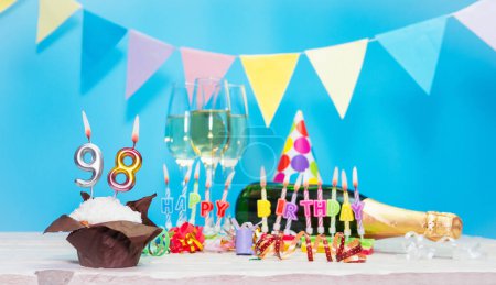 Date of birth with candles and number  98. Anniversary greeting card. Holiday decorations. Happy birthday candles. Multicolored decorations with garland