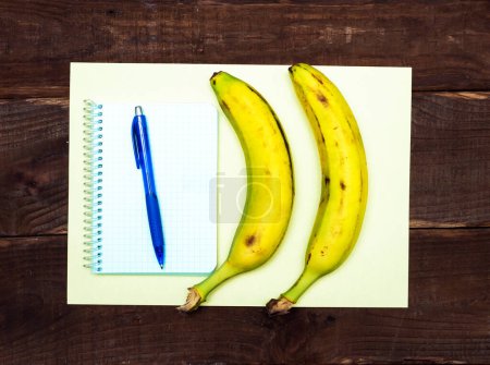 Banana with notepad with blank page for text. Notes with fruit. Pen with notebook and banana.