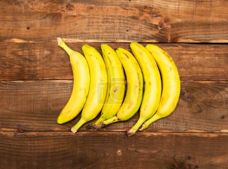Bananes sur une table en bois brun vue sur le dessus. Position figurée des bananes en forme géométrique.