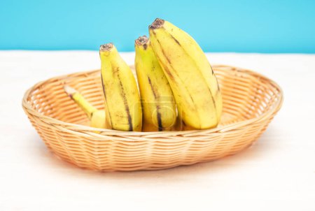 Bananas in a straw kitchen basket. Bananas on the kitchen table