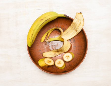 Banane tranchée sur une planche à découper de cuisine avec un couteau.