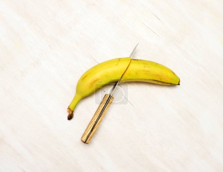 Cutting a ripe banana with a knife, top view