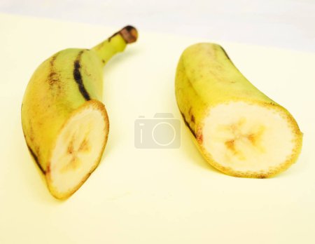 Banane mûre coupée en deux parties, sur fond jaune