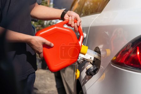 Photo for Man fills the fuel into the gas tank of car from a red canister or plastic fuel cann .maintenance repair car concept ,selective focus - Royalty Free Image