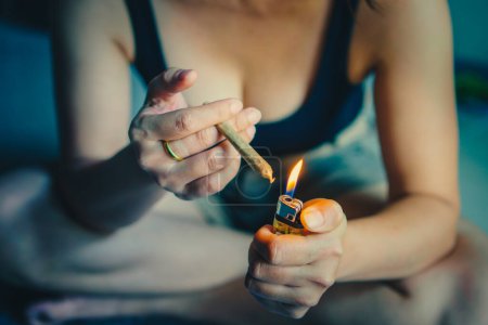 Photo for Women preparing lighting up cigarettes or marijuana joint with lighter. cannabis smoker rolling marijuana cannabis joint. Drugs narcotic concept. Legal Marijuana. - Royalty Free Image