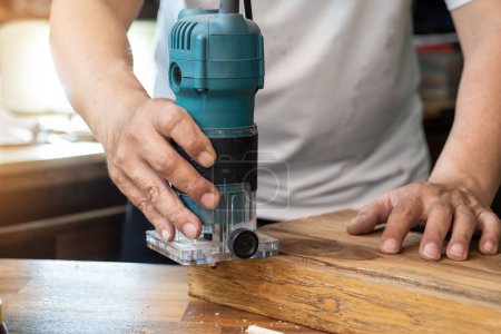 Photo for Carpenter use Router Trimmer to remove the material and to cut out the patch on wood at workshop,DIY maker and woodworking concept. selective focus - Royalty Free Image