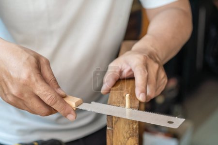 Photo for Carpenter using Japanese saw or pull saw , Cutting Wooden Dowels  on wood on table , DIY maker and woodworking concept. selective focus - Royalty Free Image