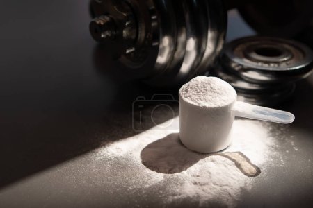 Téléchargez les photos : Whey protein powder and dumbbell background ,Sports nutrition. Fitness or healthy lifestyle concept - en image libre de droit