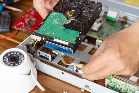 Photo for Technician remove a hard disk drive from the CCTV DVR recorder case, to install a new hard drive and upgrading to a Solid State for backup CCTV camera , electrical work and cctv concept - Royalty Free Image