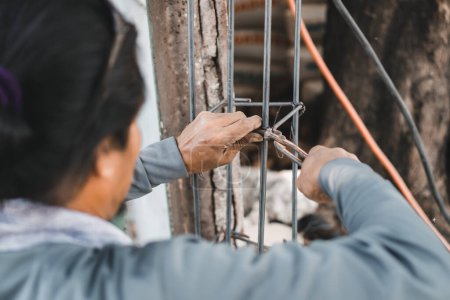 Téléchargez les photos : Les travailleurs de la construction utilisant des pinces coupantes et du fil d'acier pour lier le fil dans les structures en béton armé, la construction et le concept de l'industrie - en image libre de droit