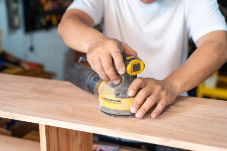 Photo for Carpenter using a random orbit sander on wood in the workshop,woodworking concept , selective focus - Royalty Free Image