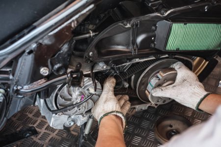 Mechaniker überprüfen den Zustand von Motorrädern oder großen Rollern Antriebsriemen. Überprüfen Sie die Riemenspannung in Motorradgaragen.