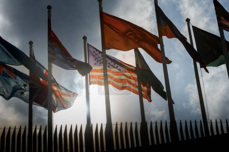 Téléchargez les photos : Association internationale du drapeau Dans le vent, oscillant avec le ciel sombre et le soleil couchant l'éclairage - en image libre de droit
