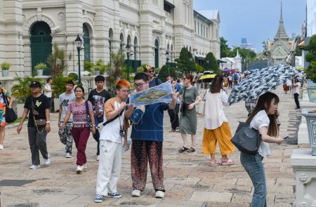 Téléchargez les photos : BANGKOK, THAÏLANDE - 17 octobre 2023 - Touristes chinois regardant la carte et visitant le Grand Palais et le Temple du Bouddha Émeraude en Thaïlande. - en image libre de droit