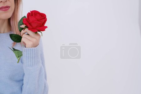 Photo for Beautiful and attractive woman dressed in baby blue holding a red rose in her hands. Self love concept. Happy. Copy space. - Royalty Free Image