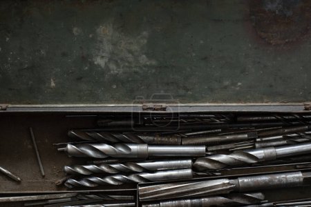 Foto de Vista superior de una caja de herramientas de metal verde abierto con puntas de óxido y polvo y acero y brocas para un taladro, con espacio para copiar - Imagen libre de derechos