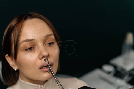 Téléchargez les photos : Le maître de studio perce les lèvres avec une aiguille - en image libre de droit