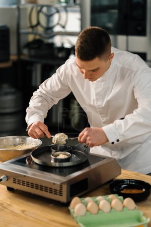 Téléchargez les photos : Un chef professionnel dans la cuisine d'un restaurant prépare des crêpes pour le petit déjeuner. Recette culinaire Poêle sur poêle - en image libre de droit