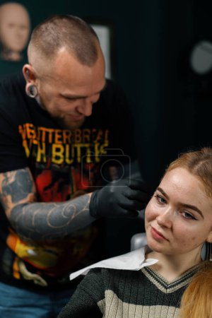 Photo for Piercing studio. a master pierces a girl's ear - Royalty Free Image