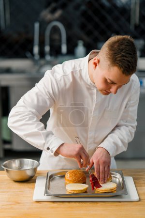 Photo for A chef butters burger buns with a brush in professional kitchen gastronomy - Royalty Free Image