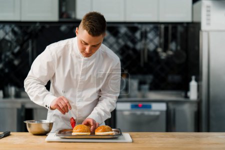Téléchargez les photos : Un chef beurres pains hamburger avec une brosse dans la gastronomie de cuisine professionnelle - en image libre de droit