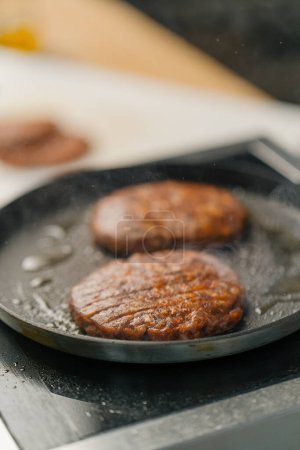 Foto de Hamburguesas hamburguesas carne en una sartén caliente deliciosas hamburguesas en cocina profesional - Imagen libre de derechos