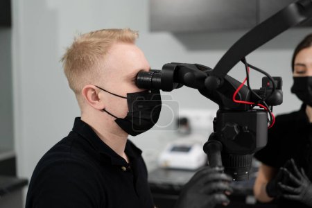 Photo for Dentistry a dentist examines a patient through microscope - Royalty Free Image