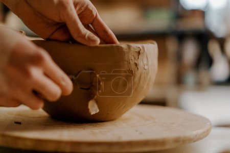 Photo for In the pottery workshop the master processes the product with loop for clay sculpts clay dishes on table - Royalty Free Image