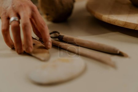 Photo for A potter works a clay vase with potter's knife in pottery workshop - Royalty Free Image