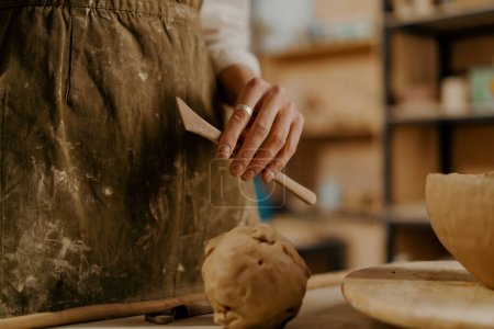 Téléchargez les photos : L'atelier de Potter, un outil pour le traitement de l'argile dans les mains de l'argile maître se trouve sur la table - en image libre de droit