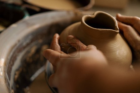 Photo for Pottery workshop a potter teaches student to sculpt jug from clay couple is engaged in pottery - Royalty Free Image