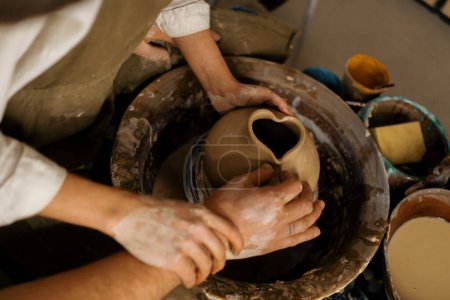 Foto de Taller de cerámica un alfarero enseña a los estudiantes a esculpir jarra de arcilla pareja se dedica a la cerámica - Imagen libre de derechos