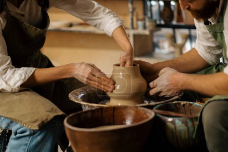 Photo for Pottery workshop a potter teaches student to sculpt jug from clay couple is engaged in pottery - Royalty Free Image