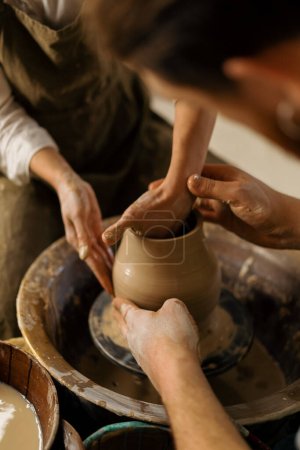 Téléchargez les photos : Atelier de poterie un potier enseigne à l'élève à sculpter cruche de couple d'argile est engagé dans la poterie - en image libre de droit