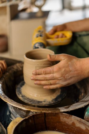 Téléchargez les photos : Un potier sèche une cruche d'argile finie dans un atelier de poterie - en image libre de droit